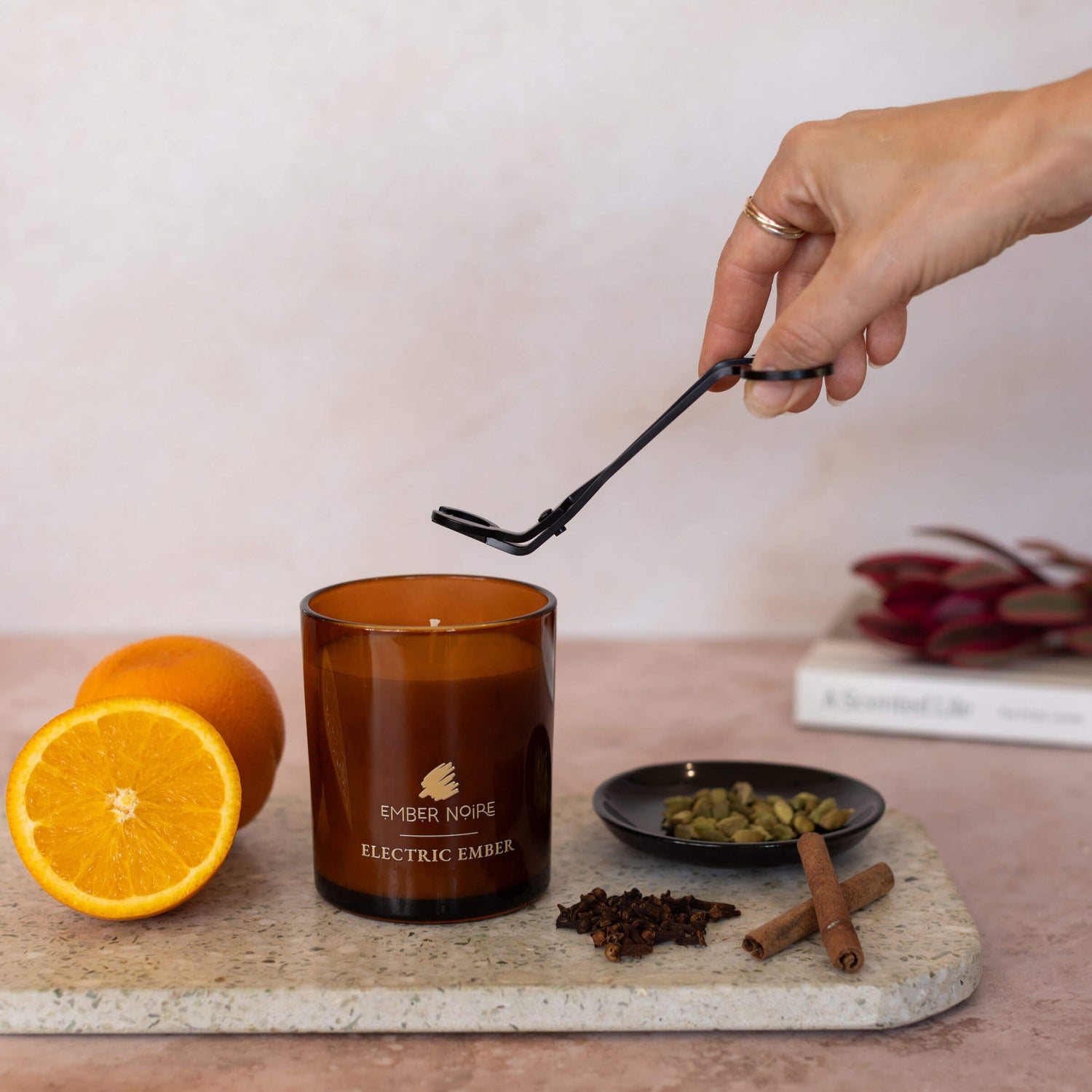 Cinnamon, clove and orange scented candle trimming the wick with scissors