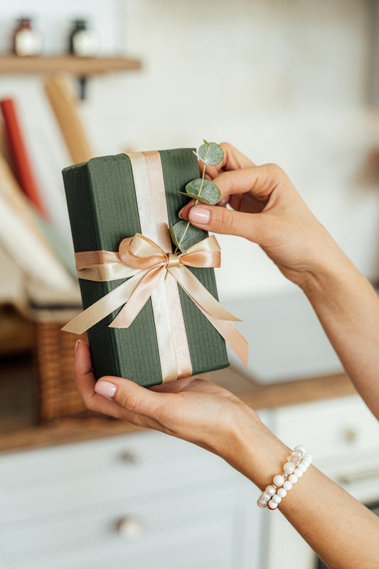 Person holding a beautifully wrapped aromatherapy gift set with ribbon