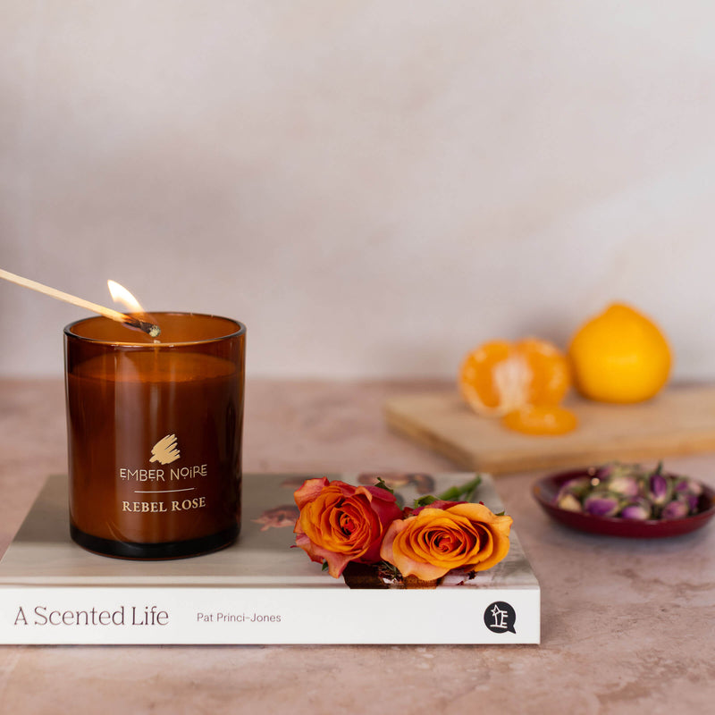 Rebel Rose floral aromatherapy candle styled with amber jar and dried florals
