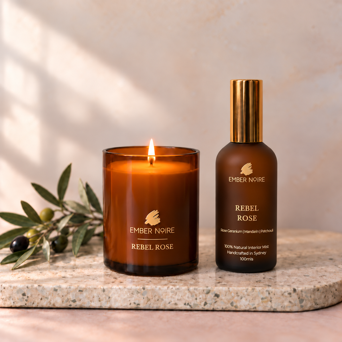Ember Noire Candle and Mist Set in Rebel Rose, lit amber glass soy candle beside the Rebel Rose interior mist on a terrazzo board