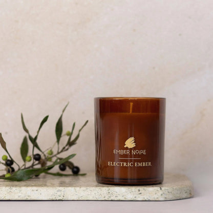 Electric Ember soy candle styled with warm spice notes in amber glass